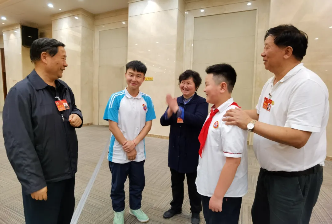 全国政协常委戚建国（左一）、全国政协文化文史和学习委员会副主任叶小文（右一）与学生亲切交谈
