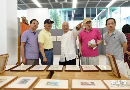 7月10日，国家级非物质文化遗产代表性传承人、杭州十竹斋艺术馆馆长魏立中（左三）向嘉宾介绍参展作品。新华社记者 韩传号 摄