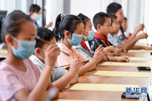 　7月30日，宁夏银川市兴庆区掌政镇新创家园社区学生在公益暑托班练习毛笔握持姿势。