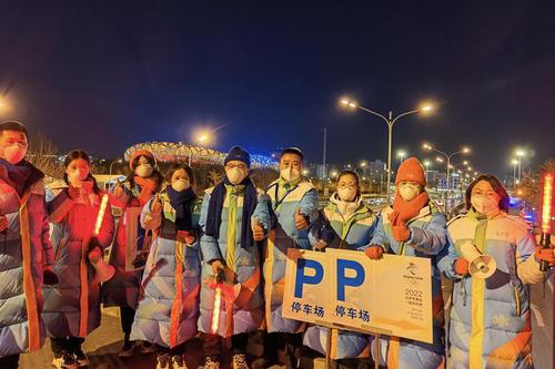 寒冷冬夜，冬奥比赛场馆外从事引导服务的志愿者们。
