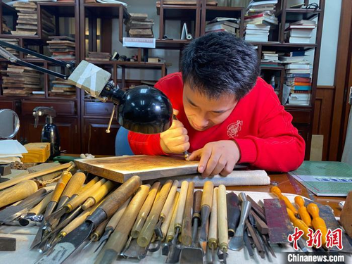 李振豪将老虎图案雕刻在棠梨木板上。　李明芮　摄