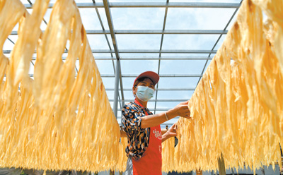 湖北省通城县依托助农平台开展消费帮扶，帮助当地特色农副产品拓宽销路。图为左港村豆制品专业合作社社员晾晒豆油皮。