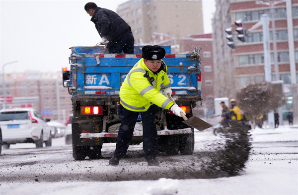 乌鲁木齐市交警支队的辅警正在向路面抛洒炉渣，防止车辆打滑。冶占飞 摄