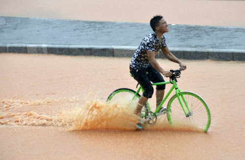 5月11日，一名行人在深圳街头冒雨骑行。