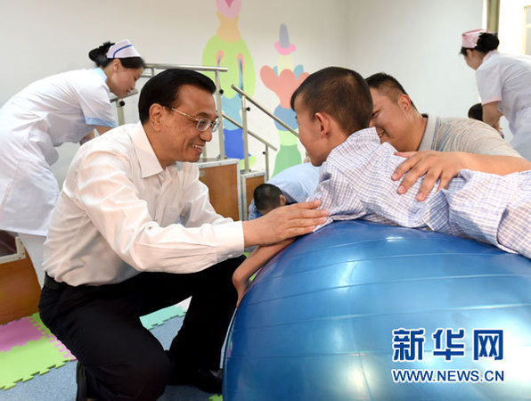 这是李克强与进行康复训练的患儿交谈。 新华社记者马占成摄