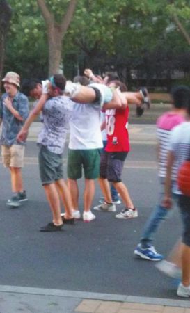 四名外籍男子一同扛起醉汉拍照。