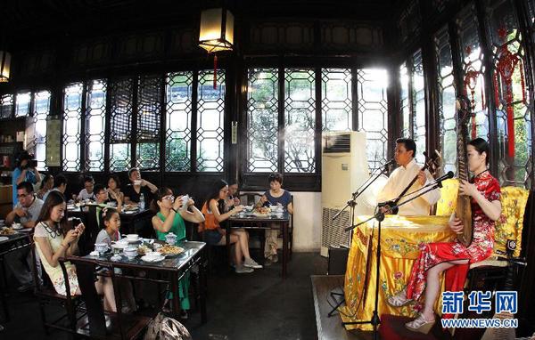 7月20日早晨，游客在参加苏州拙政园“私人定制”的早游之后边品尝当地美食边欣赏苏州评弹。为避开炎夏高温，苏州拙政园推出“私人定制”早游活动。