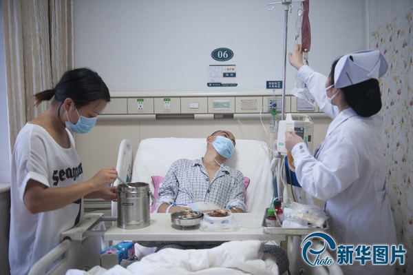 李真病床旁，向华与护士各站一边，向华把饭菜摆上小桌，护士换药瓶，李真靠在床上看着护士换药瓶，没有看他平时最爱吃的香干炒肉。