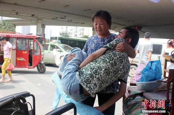 来到街头“卖唱”点，吕爱梅熟练地把儿子把下三轮车，布置场地。 马义恒 摄