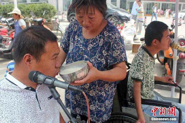 每天起床后便匆匆来到街头“卖唱”，吕爱梅只能把面汤熬好在小强和小猛唱歌间隙喂他们吃。马义恒 摄