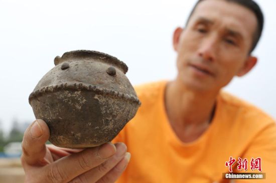 图为考古工作人员展示出土的带有腰带纹的仰韶文化时期的小黑陶罐 图为考古工作人员展示出土的带有腰带纹的仰韶文化时期的小黑陶罐