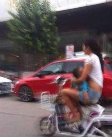 妈妈边骑车边给孩子喂奶。