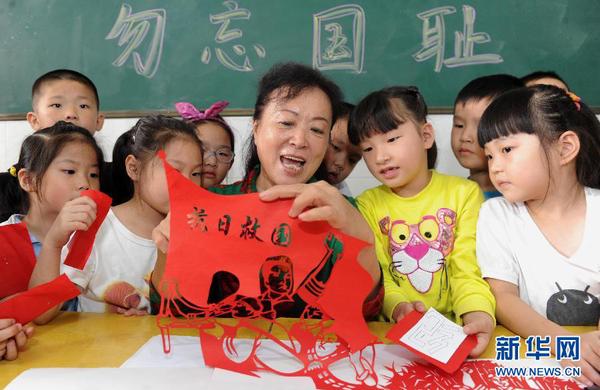 9月17日，剪纸老师宋丽文（中）在教孩子们制作以纪念“九一八”为主题的剪纸作品。当日，安徽合肥市蚌埠路第三小学开展“勿忘国耻，振兴中华”为主题的“九一八”爱国主义教育活动，社区剪纸老师宋丽文现场教孩子创作剪纸作品，教育学生铭记历史、热爱祖国。新华社记者 杜宇 摄