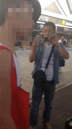 便衣男子手持数码相机和手机拍摄。
