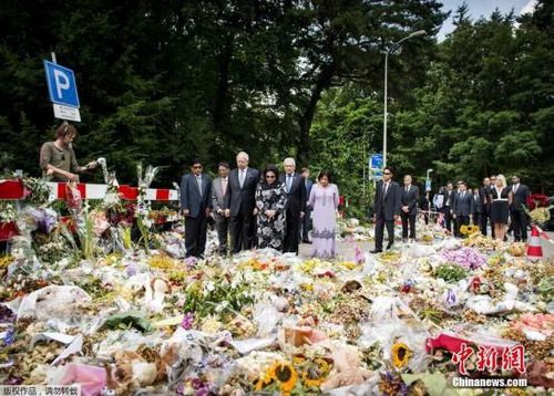 2014年7月31日，荷兰希尔弗瑟姆，马来西亚总理纳吉布携妻子在当地一处军事基地外献花。法医专家正在该基地内对马航MH17失事航班遇难者的遗体进行辨认和恢复。