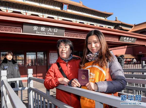 12月3日，一名教师（右）在故宫博物院入口处展示教师资格证。