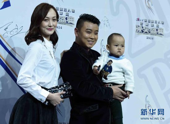 2月1日，前乒乓球国手王皓（中）抱着儿子小乐天与妻子闫博雅在颁奖典礼红毯仪式上合影。当日，“2014CCTV体坛风云人物年度评选”颁奖典礼在京举行。 新华社记者公磊摄