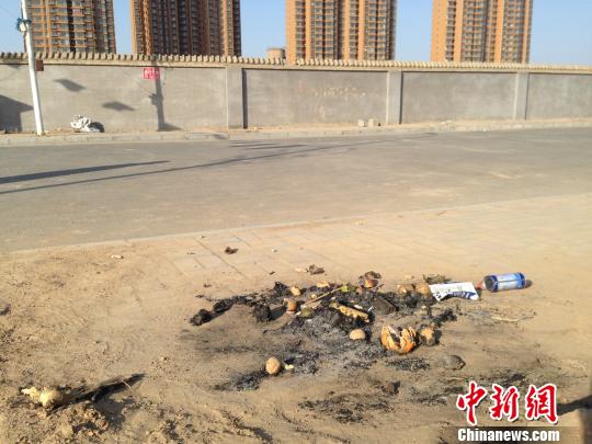 亲人在何建华遇害处燃烧的纸钱和祭品。　王天译摄