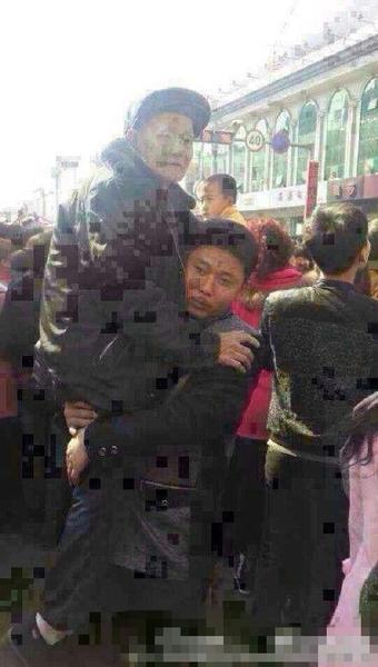 被抱起的老者，年纪大约70多岁，手持拐杖，穿戴一新。
