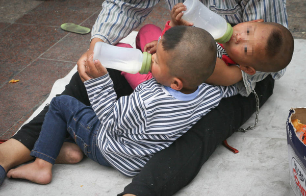 2015年5月1日，一位男子在北京站前广场地铁口将一对双胞胎用铁链拴在腰间乞讨，引来游客围观，路人报警。