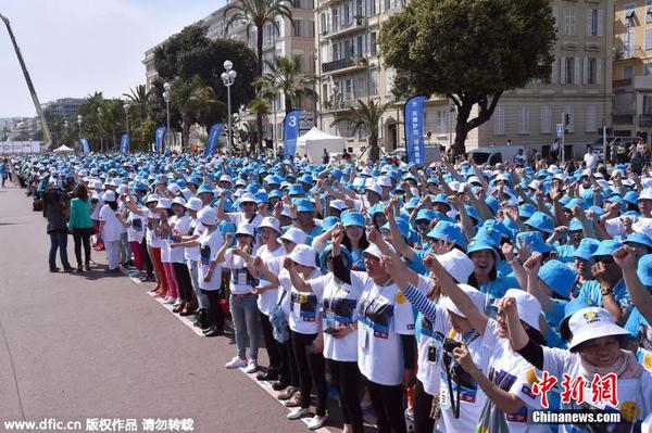当地时间2015年5月8日，法国尼斯，中国某集团庆祝公司20周年纪念日，该集团半数员工约6400人获得4天假期，分别在巴黎和尼斯旅游两天。图为公司员工在尼斯的海滨大道庆祝。