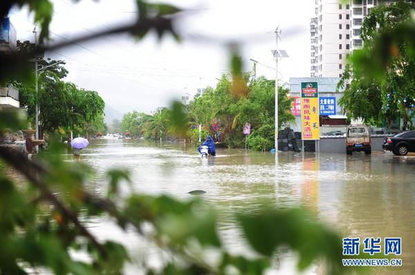 6月23日，在海南省三亚市，人们在积水路段涉水前行。今年第8号台风“鲸鱼”已于6月22日18时50分左右在海南省万宁市沿海登陆，台风给三亚带来了强风降雨天气，影响市民正常出行。新华社发（沙晓峰 摄）