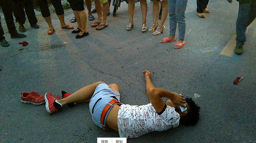 7月10日，安徽淮北，一名青年男性车祸后倒在路上，众人围观