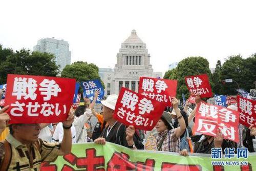 2015年7月14日，日本民众在国会外集会，手举标语牌，高喊口号示威，抗议新安保法