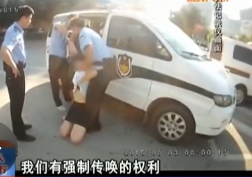 就在警察想把她从地上拉起来时，该女子突然伸手解开自己上衣衣扣