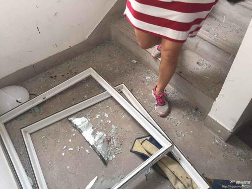 由于8月12日晚的爆炸，附近小区楼房受损严重，楼道的地上有很多玻璃渣和窗框。（图片源于中国之声微博）