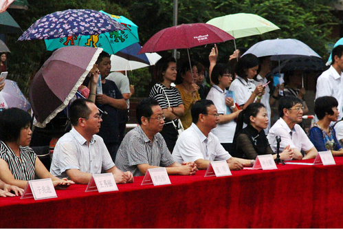 在主席台上观看的校领导也坚持不打伞陪学生一起淋雨，身旁站满了打伞观看的家长。
