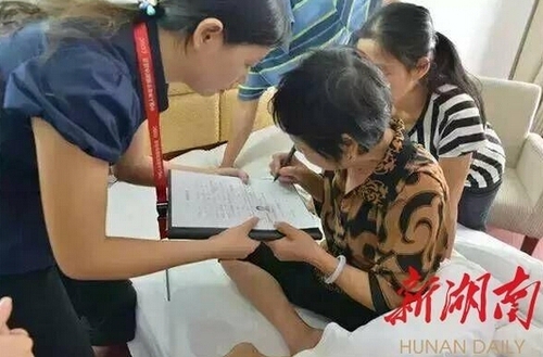 图为梅雄家人在器官捐献意愿书上签字。