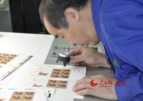 印刷车间里的工作人员正在用放大镜检查印刷效果。(人民网 王鹤瑾 摄)