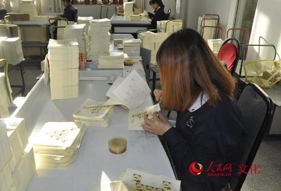 检票员正在仔细检查每一张邮票。(人民网 王鹤瑾 摄)