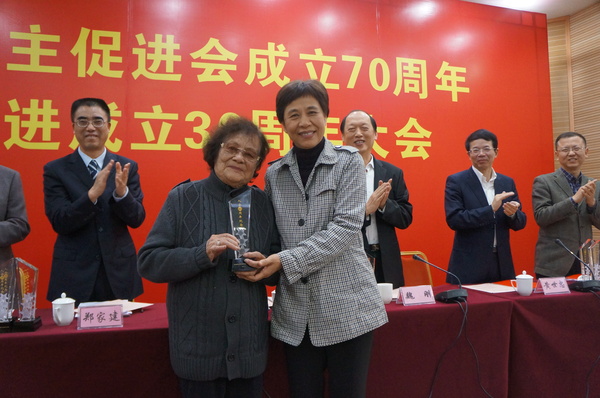 厦门市统战部部长黄菱给入会60周年97岁高龄的民进会员谢植桂颁发荣誉奖杯。