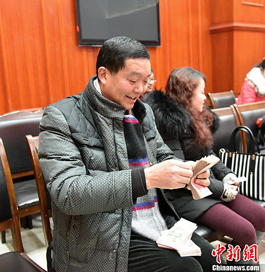 图为农民工清点自己领到的钱。中新社记者
