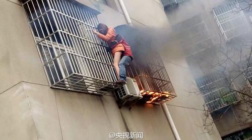 近日，湖北一户居民家着火冒出滚滚浓烟，一女子被防盗网困住！对面小区整理包裹的快递员张洋见状跑来，徒手爬上阳台，用手肘使劲撞开防盗网，终将女子救出！（央视记者吴绍钧）