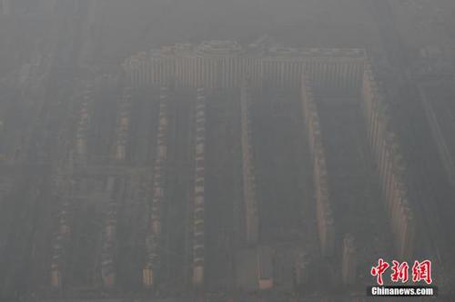 资料图：2015年12月21日，北京上空航拍空气重污染，地面建筑若隐若现。12月18日，北京再次发布红色预警，12月19日7时至12月22日24时启动空气重污染红色预警措施。实施机动车单双号行驶、建议中小学幼儿园停课等措施。 <a target='_blank' href='http://www.chinanews.com/'>中新社</a>记者 廖攀 摄