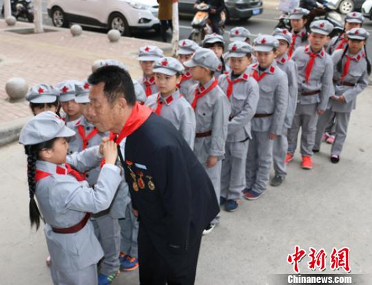受谷殿明血雷锋事迹的感染，雷锋小标兵为这位“活雷锋”爷爷系上红领巾。　郭园 摄
