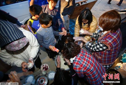 当地时间4月17日，志愿者在公园的空地上制作饭团发放给小朋友。