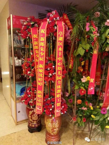 酒店门口摆有不少宾客送来的祝福花篮，其中一个花篮署名为“亭湖区永丰中心幼儿园全体教职工贺”。