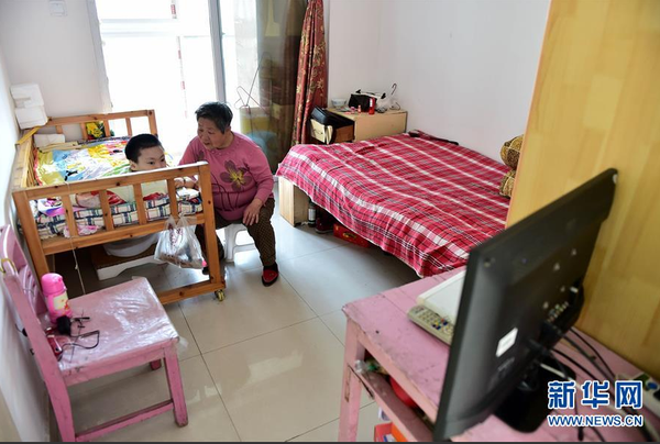 　5月19日，谢秀英在陪“小孙女”梦云看电视。