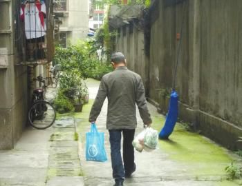 成都某中学外的小区内，一家长用中午空闲时间给住在这里的孩子买菜做饭。