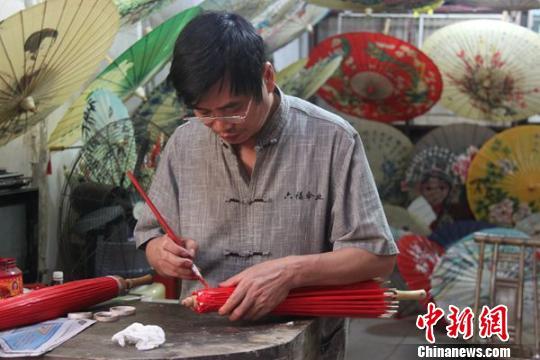 油纸伞传人毕六福正在为油纸伞上色。 邹立杨 摄 邹立扬 摄