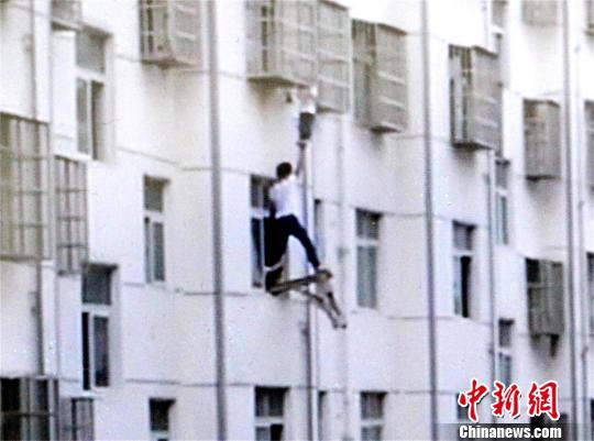 几名业主固定板凳，一名业主站上板凳托举男孩双脚 宋俊初 摄