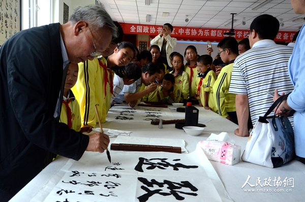 图片说明： 书画室委员与学生共同创作书法作品。