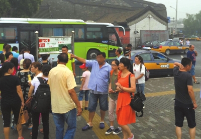蓝衣男子在路边游说游客坐他们的小车