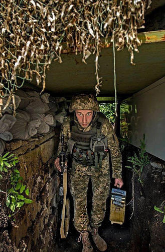 分别手持AK步枪和弹药箱的乌政府军士兵在掩体中留影。