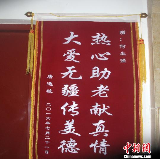 唐逸敏侄女赠送的锦旗挂在社区走廊的墙壁上。　杨东 摄