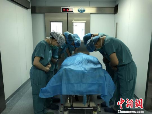 器官摘除手术结束后，医护人员向杨先松的遗体默哀致敬。　李猛 摄